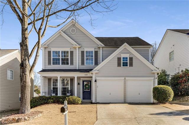 Front exterior of a traditional two-story home in Kingsgate, Woodstock GA featuring brick accents, two-car garage, and landscaped yard